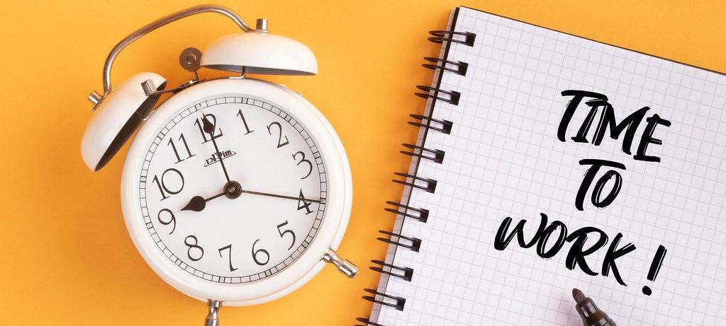 Ein Wecker und ein Notizblock mit der Aufschrift "Time to Work"