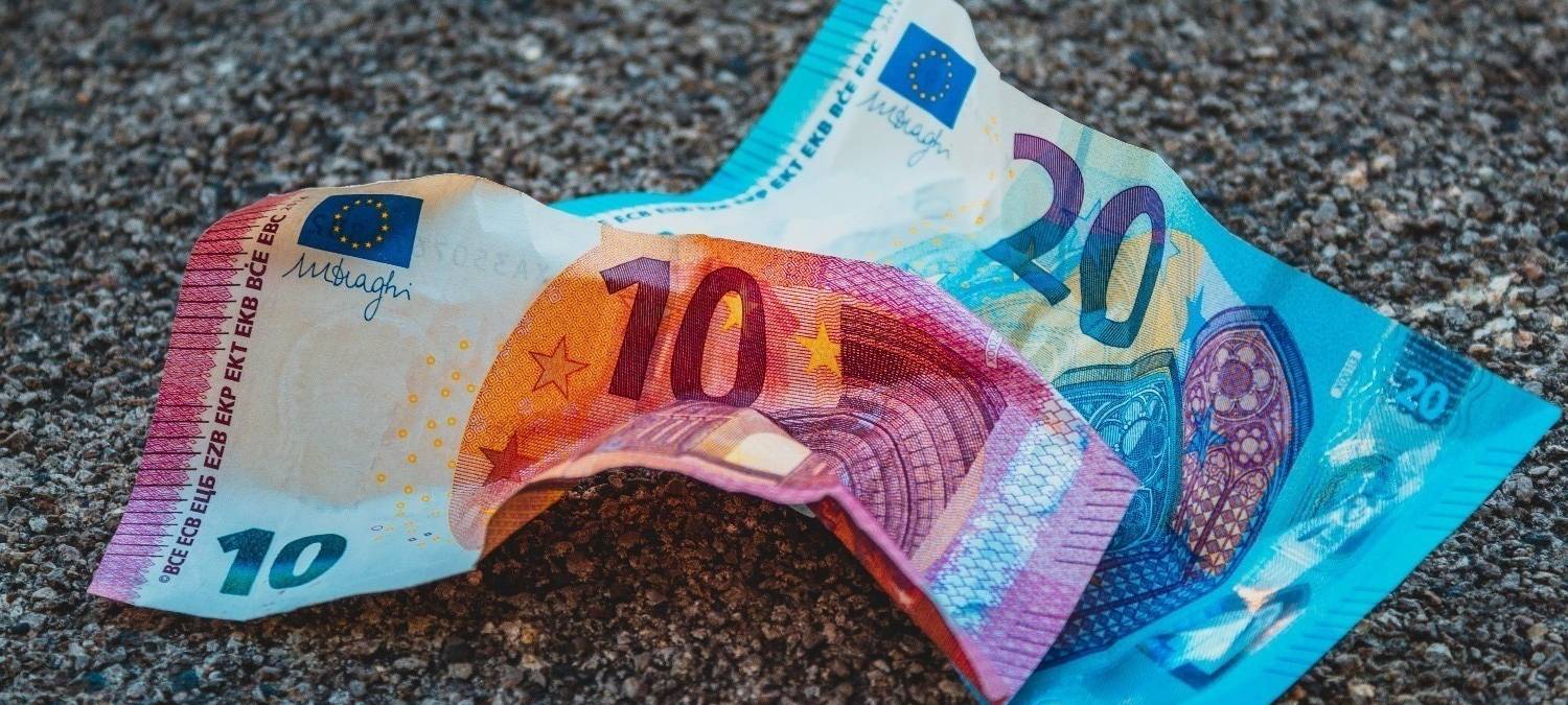 Zusammengeknitterte Geldscheine auf dem Boden.