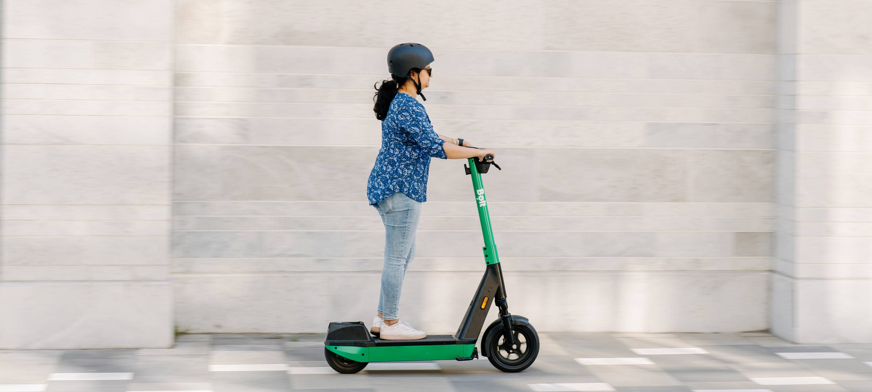 Eine Frau fährt auf einem E-Scooter von Bolt.