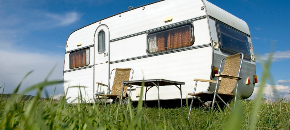 Ein Wohnwagen steht auf einem großen, grünen Feld.